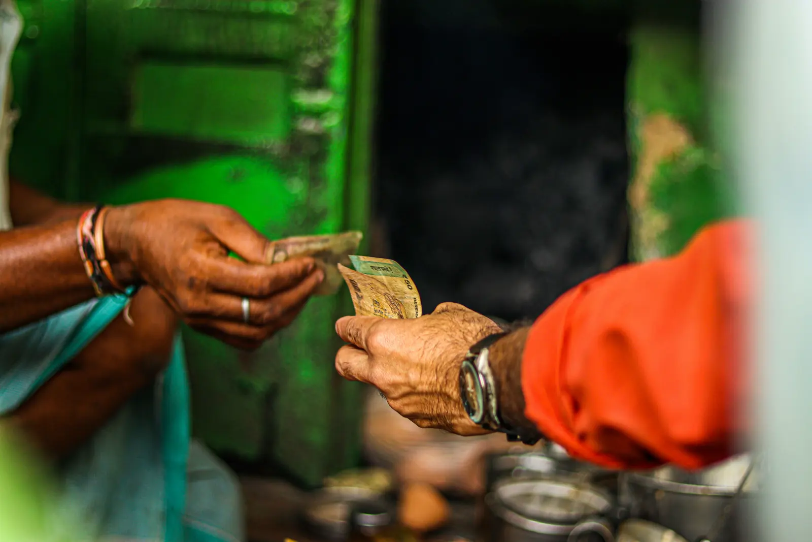 Rupee notes passing between two hands at a market stall