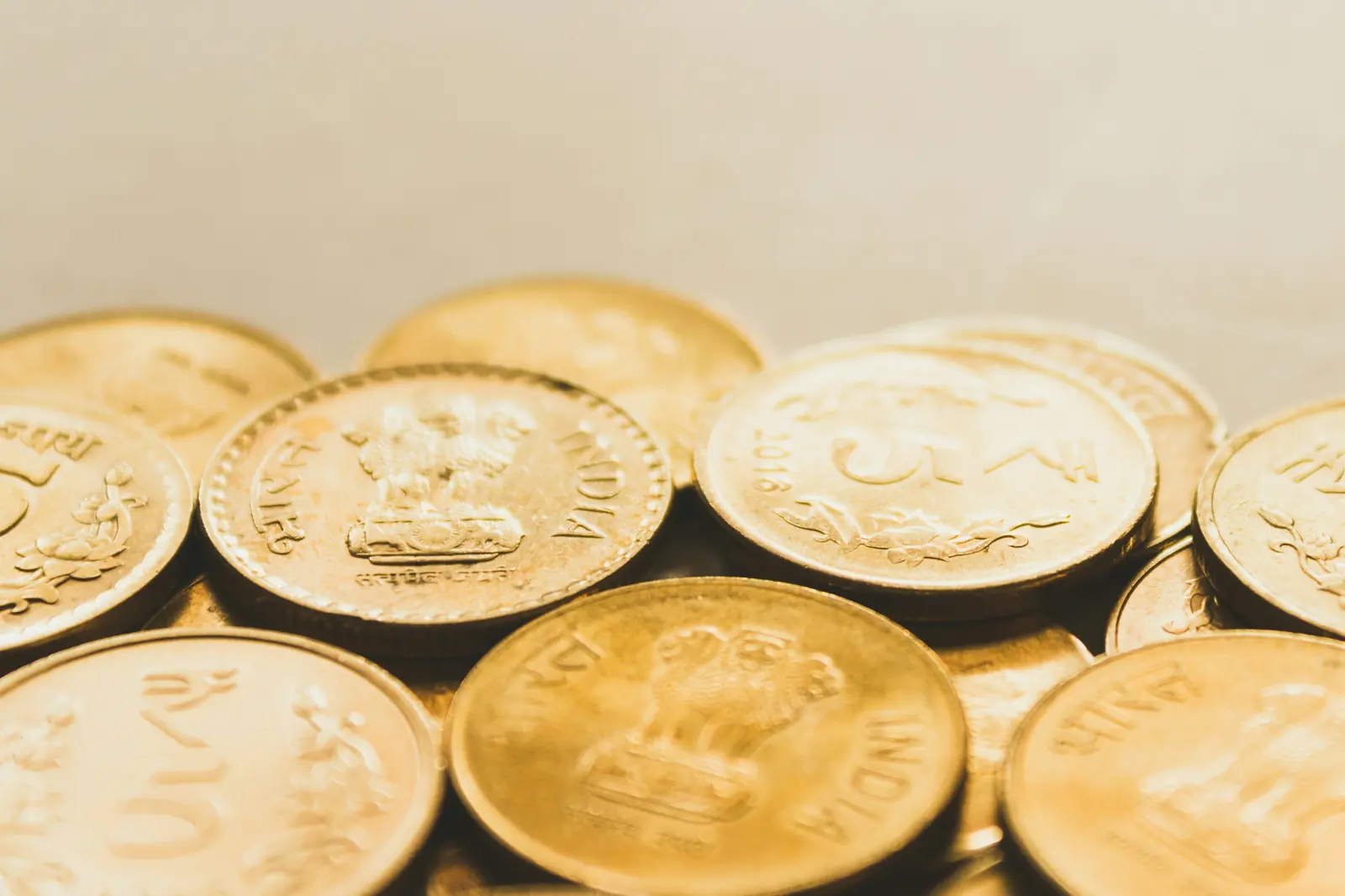 Close-up of gold-coloured rupee coins with the lion emblem