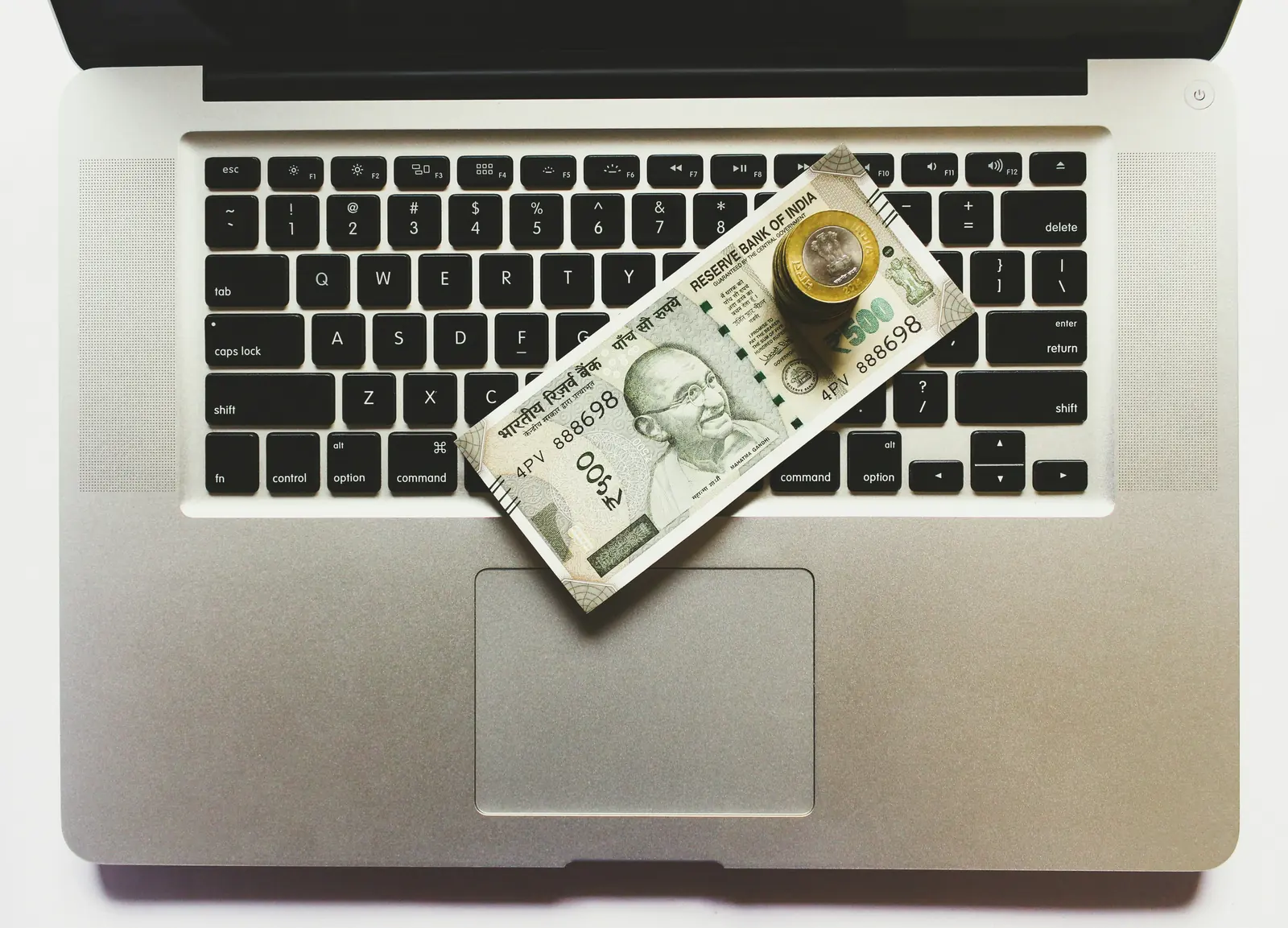 ₹500 note and rupee coins on a laptop keyboard