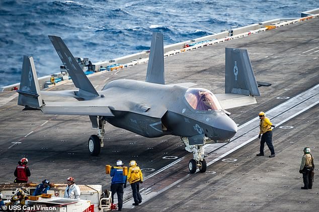 F-35 fighter jet on deck of USS Carl Vinson, crew members guiding aircraft.